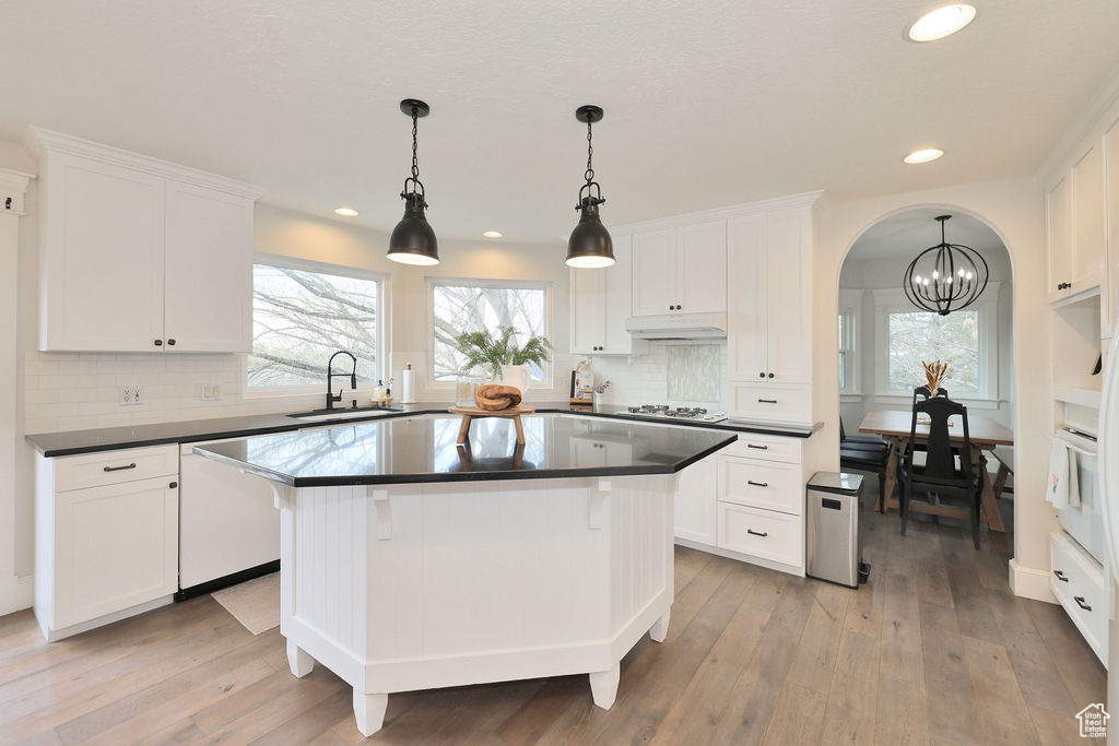 Kitchen with tasteful backsplash, pendant lighting, a center island, and light hardwood / wood-style floors