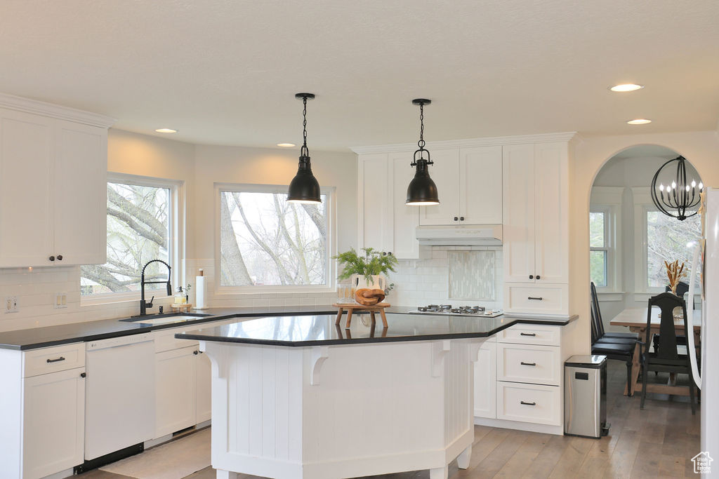 Kitchen with sink, hanging light fixtures, a center island, and white dishwasher
