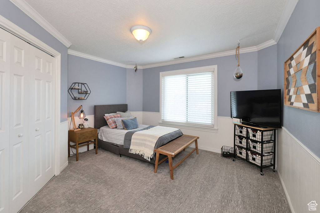 Bedroom with light colored carpet, a closet, and crown molding