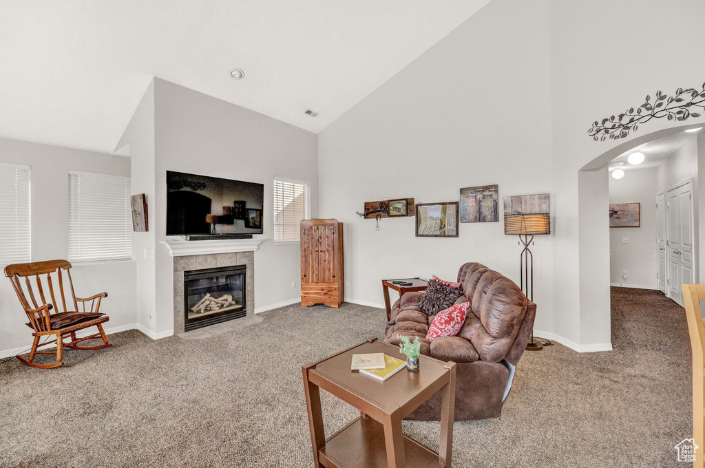 Carpeted living room with high vaulted ceiling and a fireplace