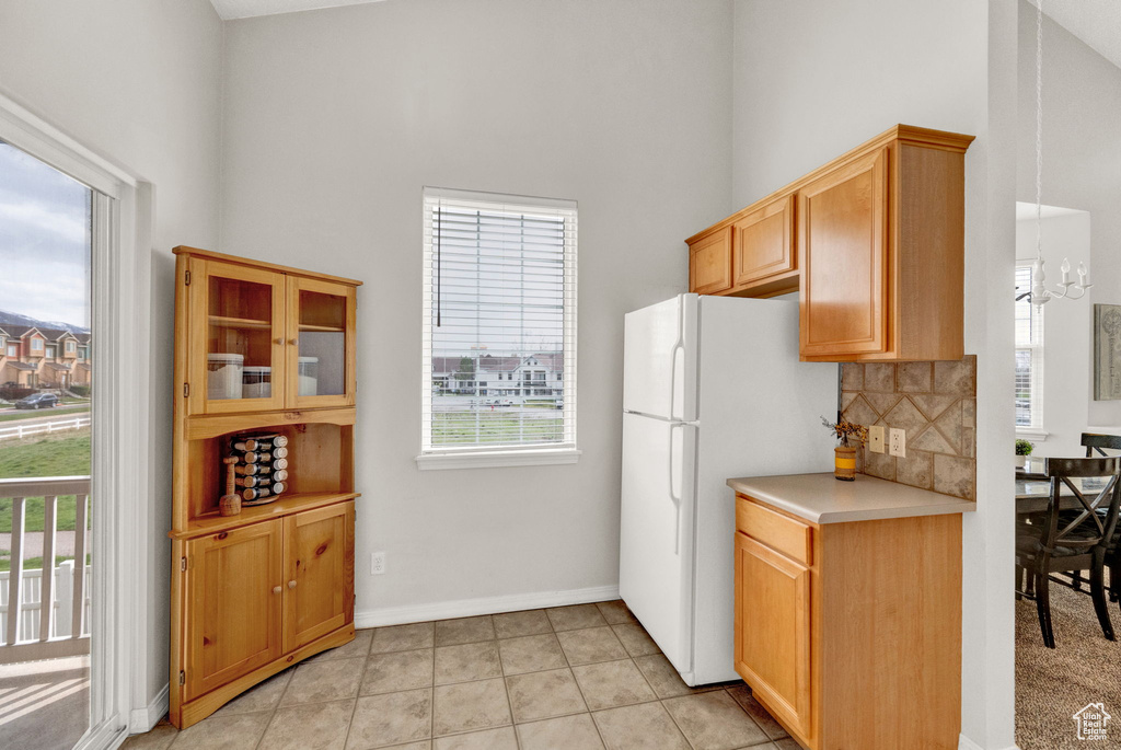 Kitchen featuring a high ceiling, tasteful backsplash, white fridge, and light tile flooring