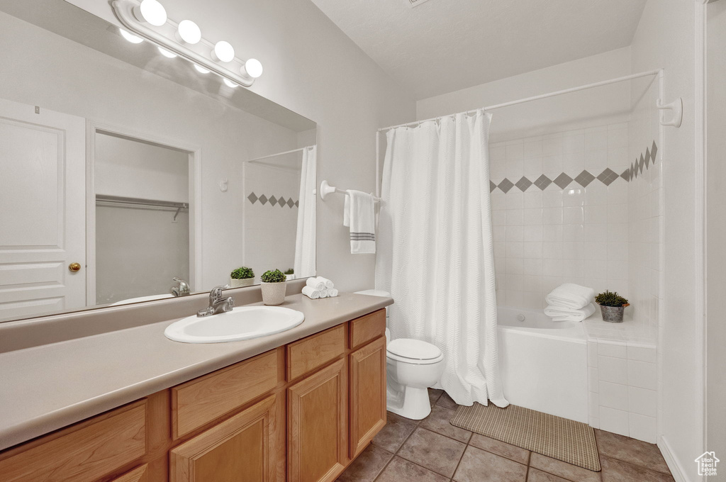 Full bathroom with shower / bath combo, toilet, tile floors, and vanity with extensive cabinet space