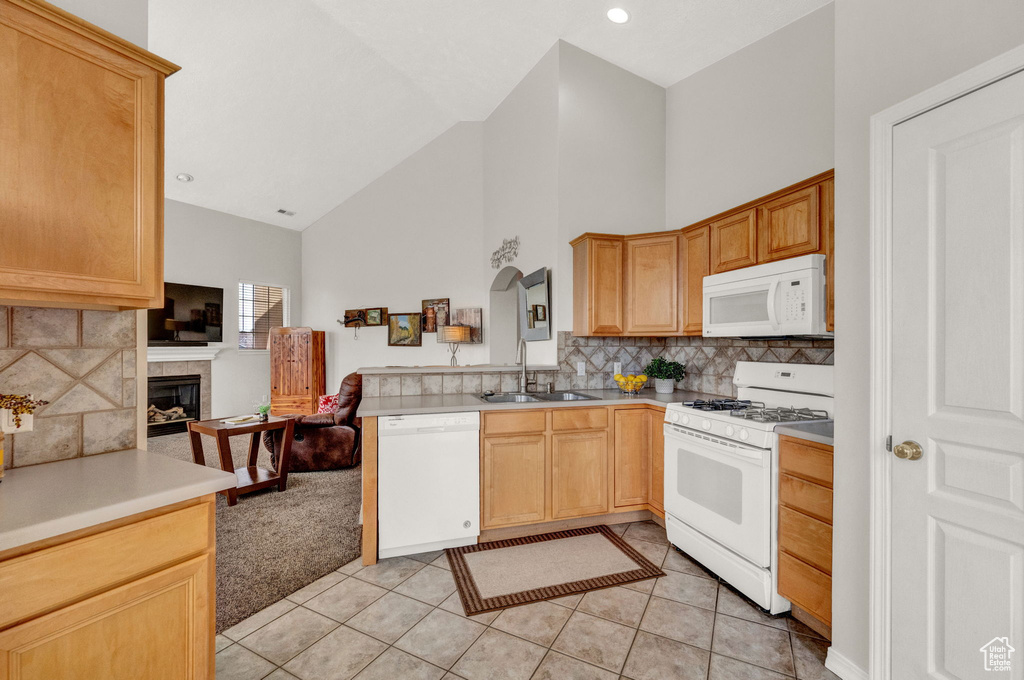 Kitchen featuring light tile floors, high vaulted ceiling, white appliances, a tiled fireplace, and backsplash
