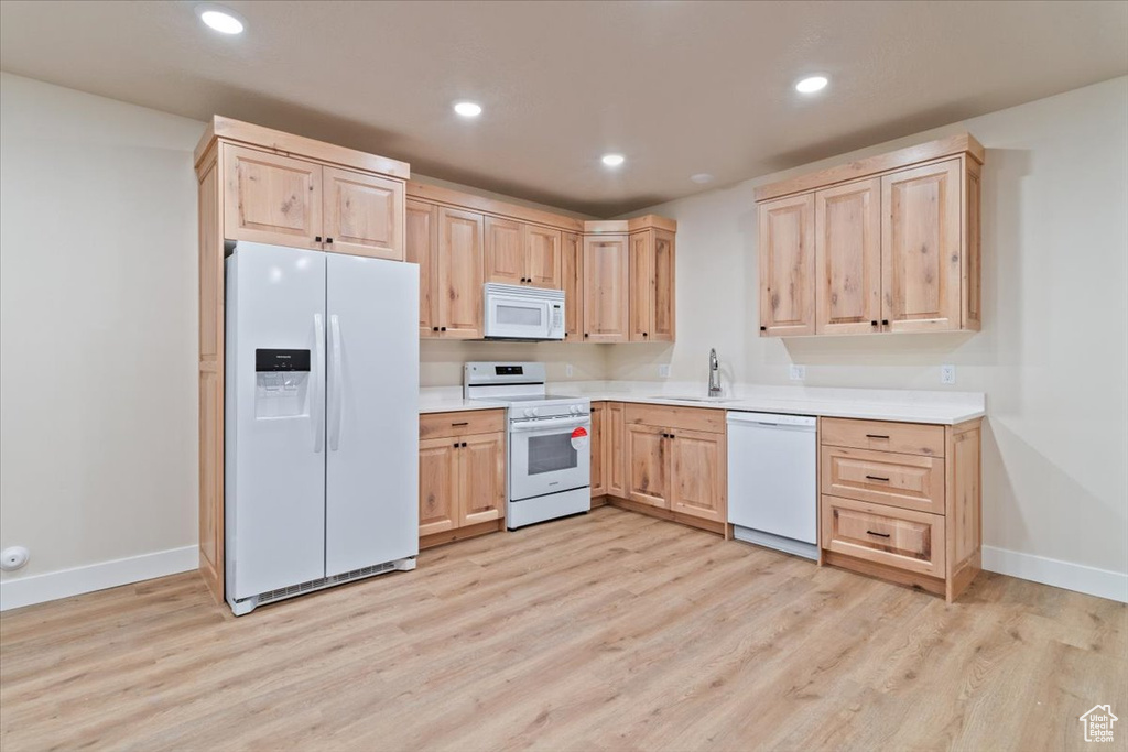 Kitchen with sink, light brown cabinets, white appliances, and light wood-type flooring
