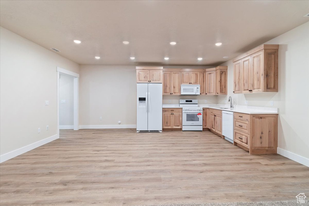 Kitchen featuring light brown cabinets, white appliances, light hardwood / wood-style floors, and sink