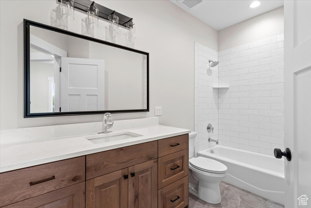 Full bathroom featuring vanity, tile floors, toilet, and tiled shower / bath