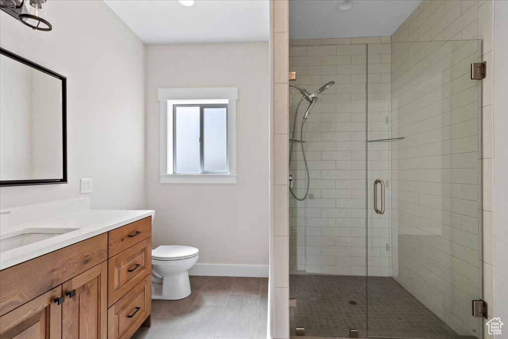 Bathroom featuring tile floors, vanity, toilet, and walk in shower