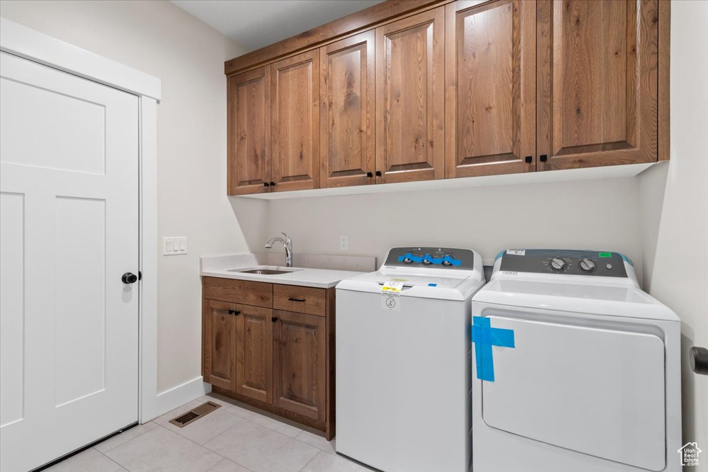 Laundry room with cabinets, light tile floors, separate washer and dryer, and sink