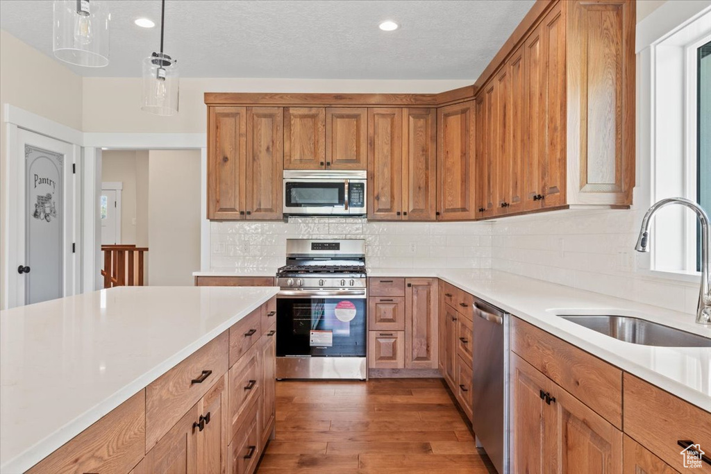 Kitchen featuring sink, backsplash, hardwood / wood-style flooring, and stainless steel appliances