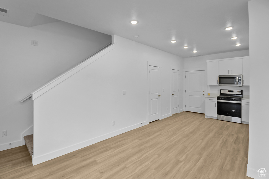 Kitchen with white cabinets, appliances with stainless steel finishes, and light hardwood / wood-style floors