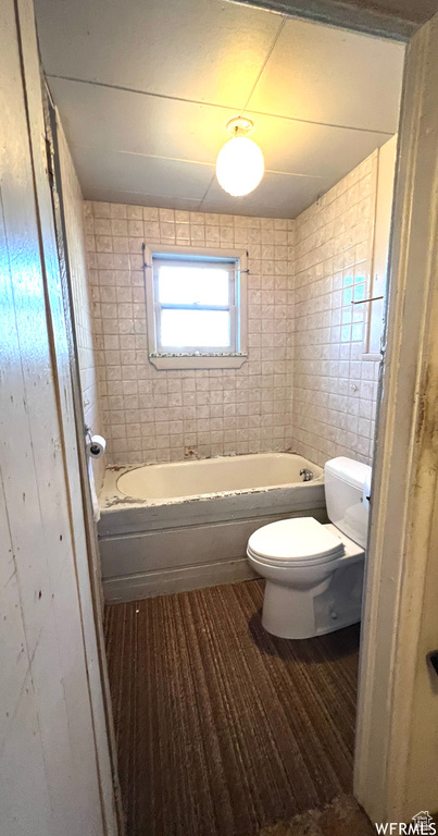 Bathroom featuring wood-type flooring, tiled shower / bath, and toilet