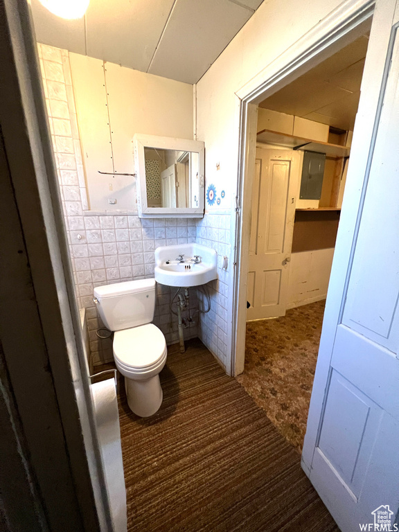 Bathroom with tile walls, tile floors, toilet, sink, and tasteful backsplash