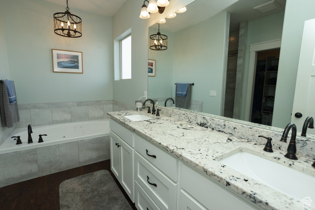Bathroom with double vanity, a relaxing tiled bath, and a notable chandelier