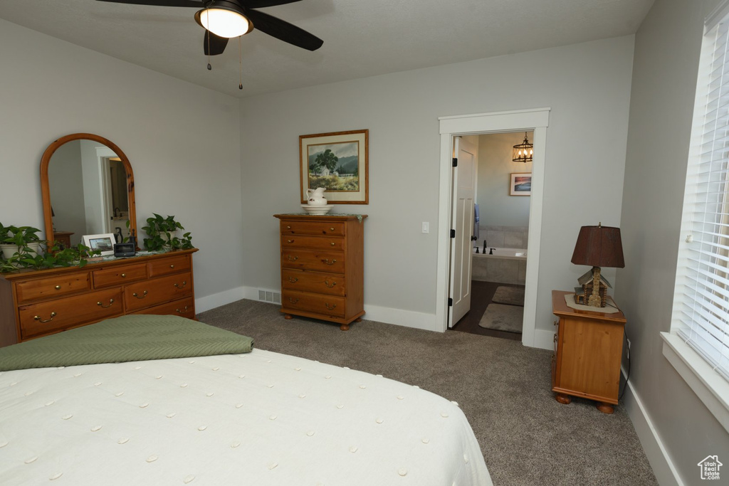 Bedroom with dark colored carpet, connected bathroom, and ceiling fan