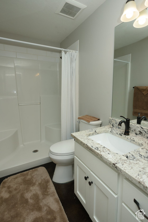 Bathroom with a shower with shower curtain, large vanity, and toilet