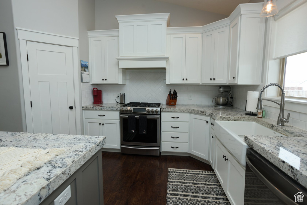 Kitchen with white cabinetry, tasteful backsplash, stainless steel gas range, and dark hardwood / wood-style floors