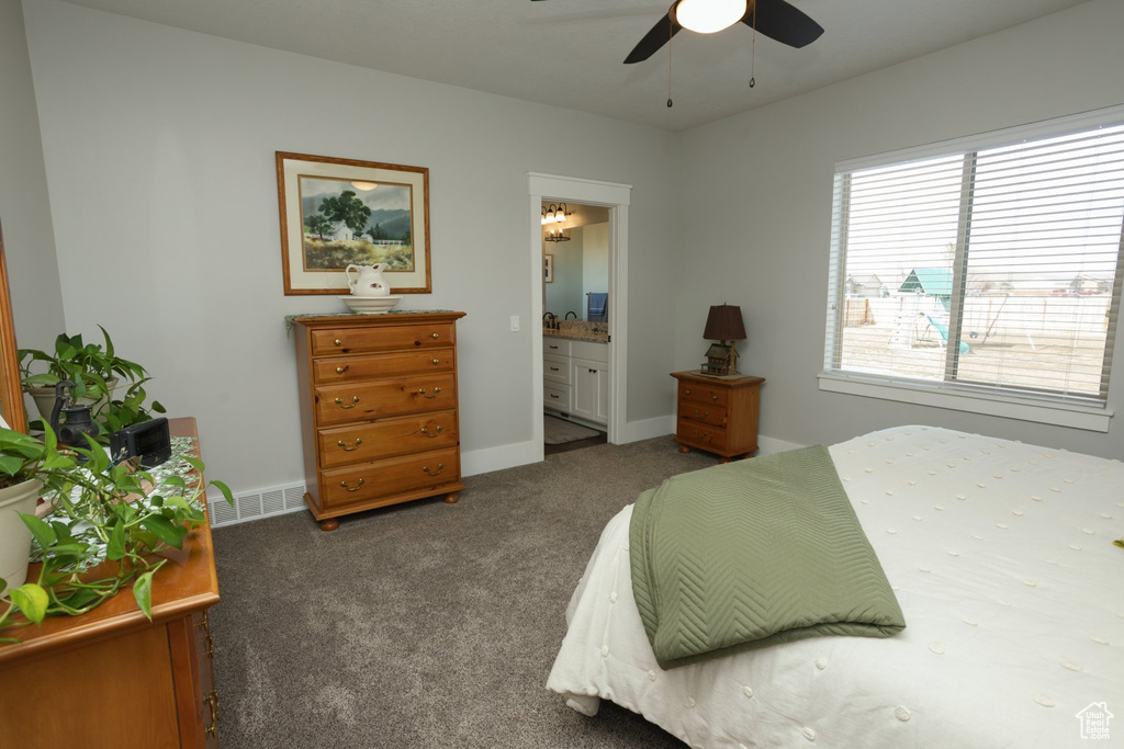 Carpeted bedroom featuring ensuite bath and ceiling fan with notable chandelier