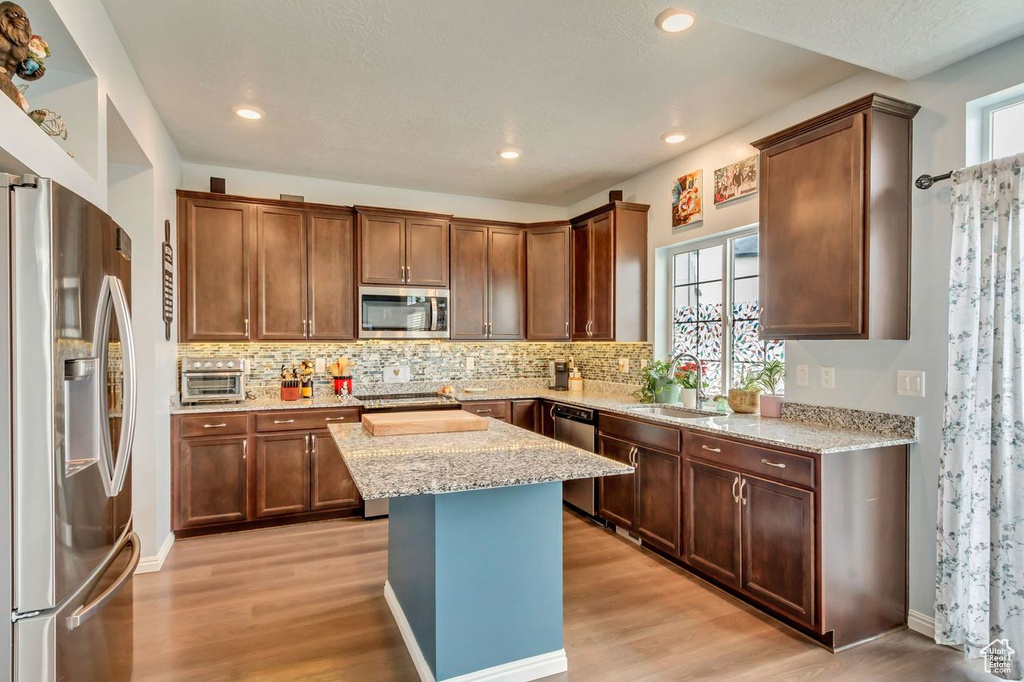 Kitchen featuring appliances with stainless steel finishes, a healthy amount of sunlight, and light hardwood / wood-style floors