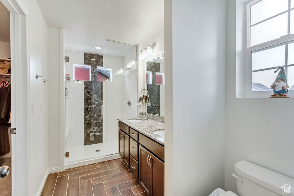 Bathroom with parquet flooring, dual vanity, walk in shower, and toilet