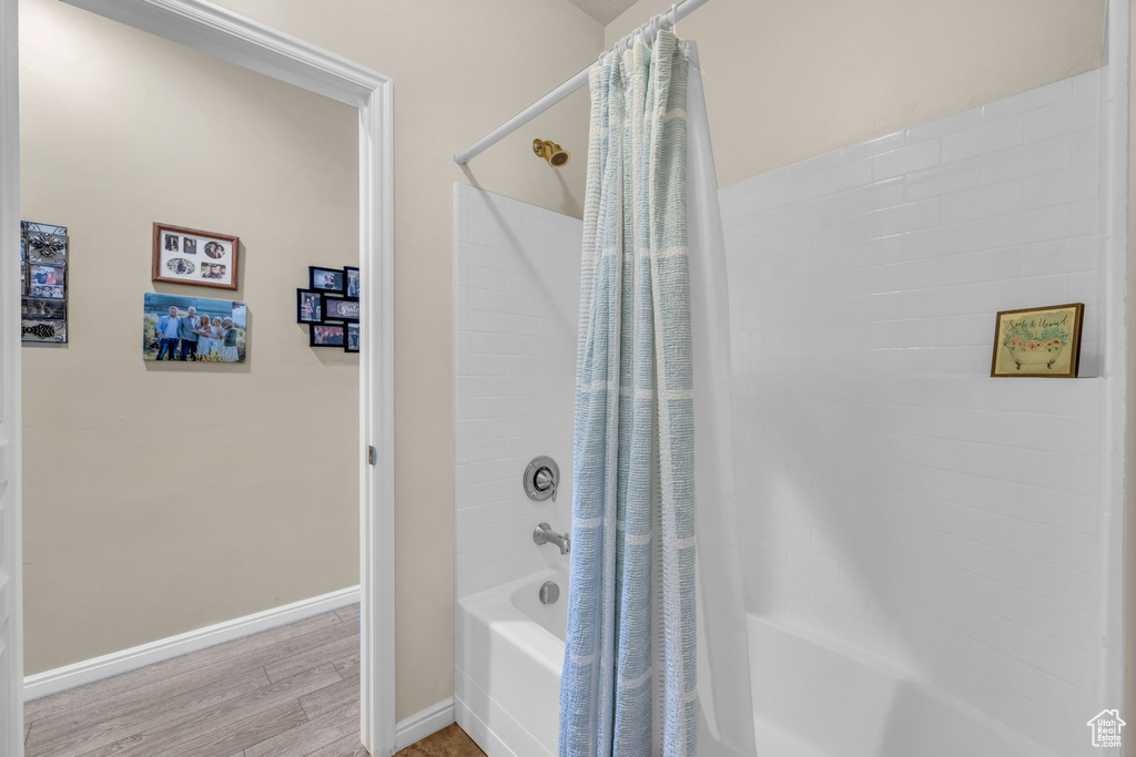 Bathroom with shower / tub combo with curtain and hardwood / wood-style flooring