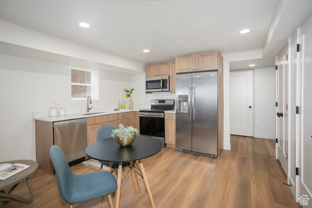 Kitchen featuring light brown cabinetry, sink, appliances with stainless steel finishes, and light hardwood / wood-style flooring