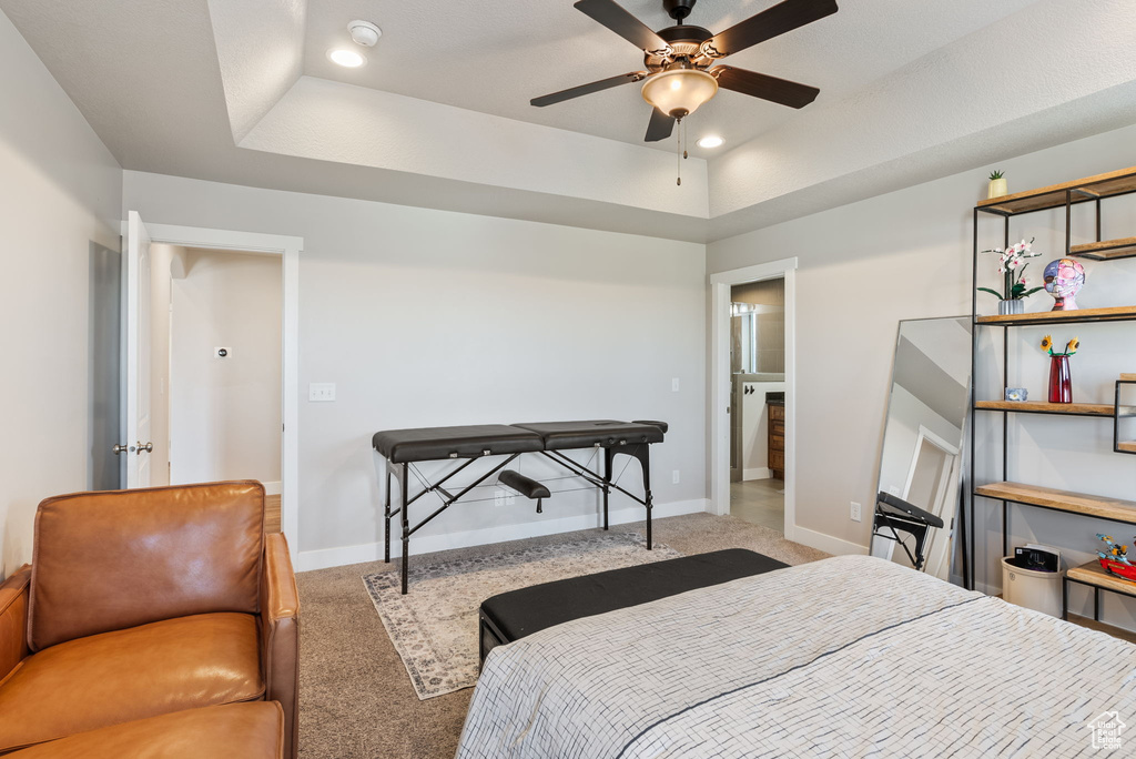 Bedroom with a tray ceiling, carpet flooring, and ceiling fan