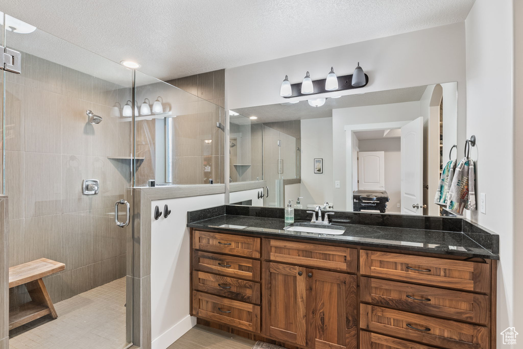 Bathroom featuring vanity, a textured ceiling, tile floors, and a shower with shower door
