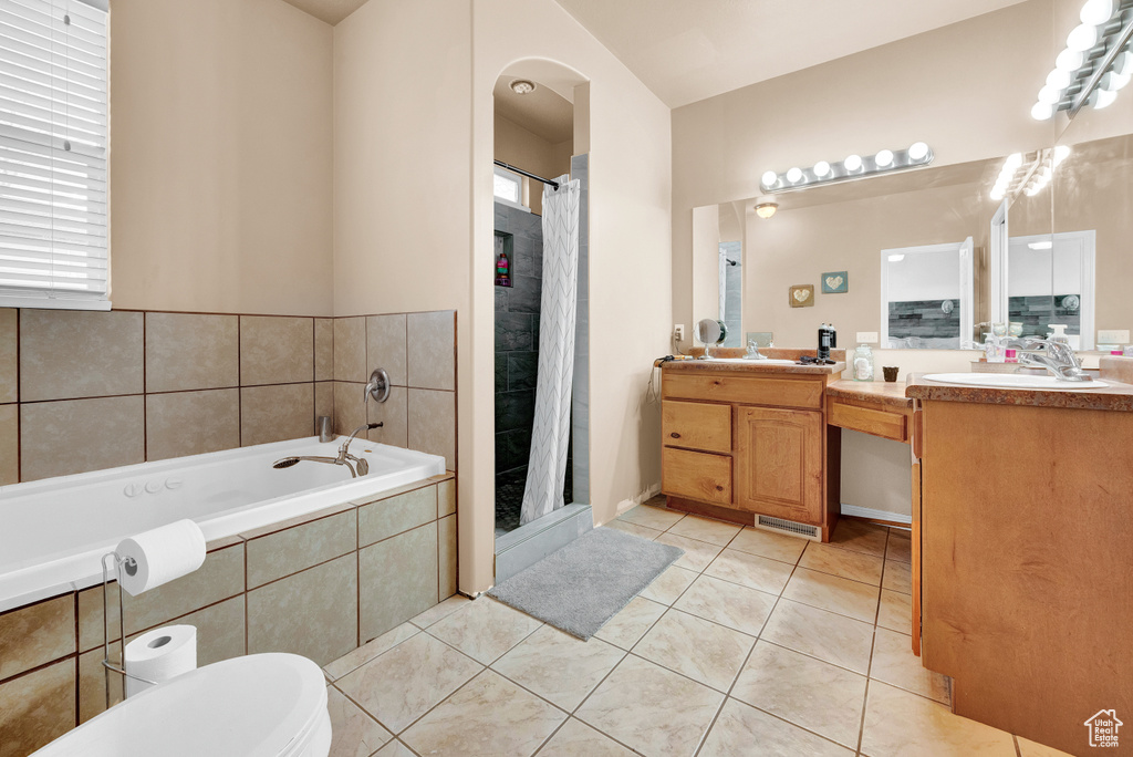 Bathroom with tile flooring, tiled tub, oversized vanity, toilet, and double sink