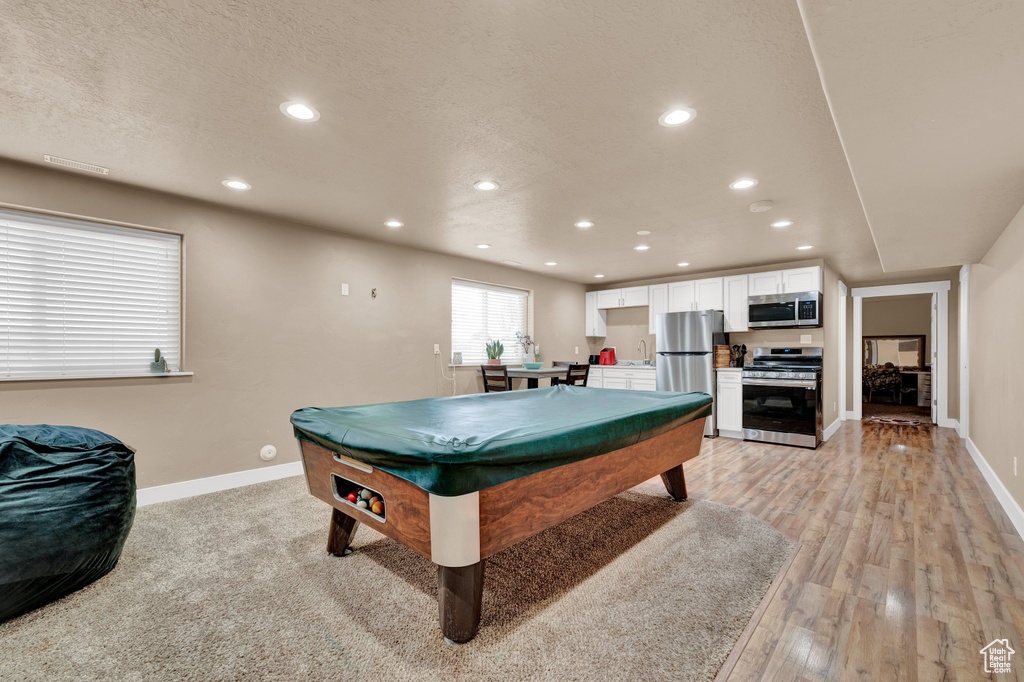 Game room featuring sink, light wood-type flooring, pool table, and a textured ceiling