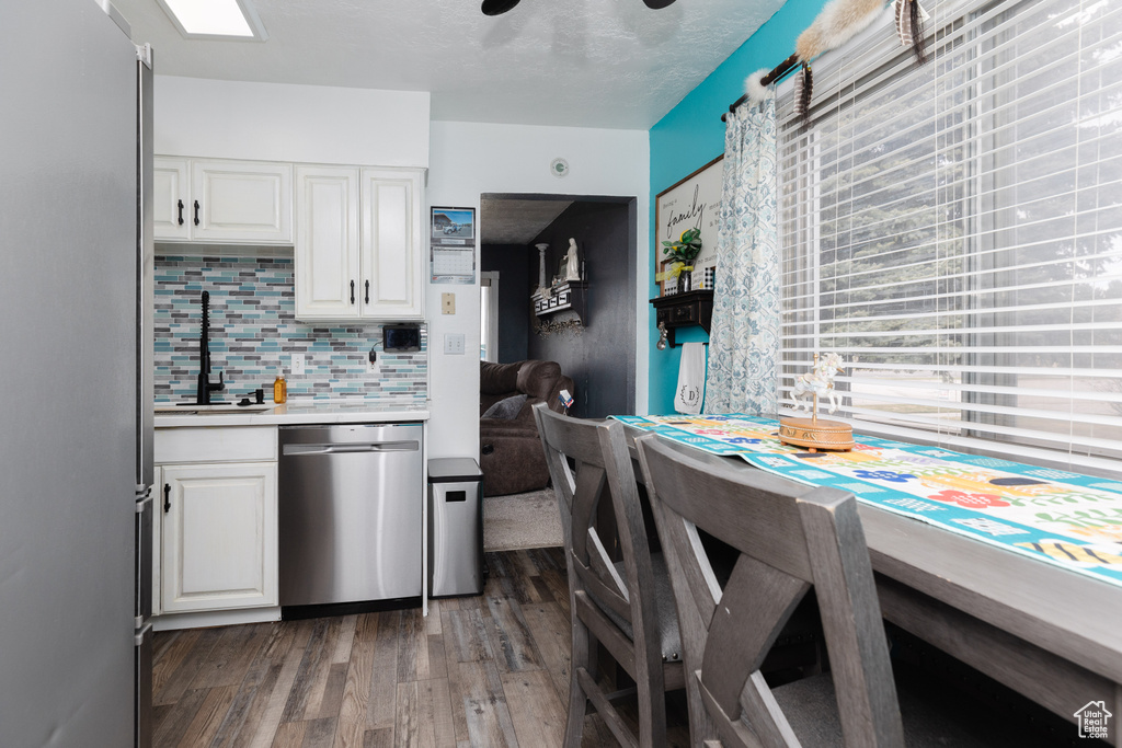 Kitchen with stainless steel appliances, sink, tasteful backsplash, dark hardwood / wood-style floors, and white cabinetry