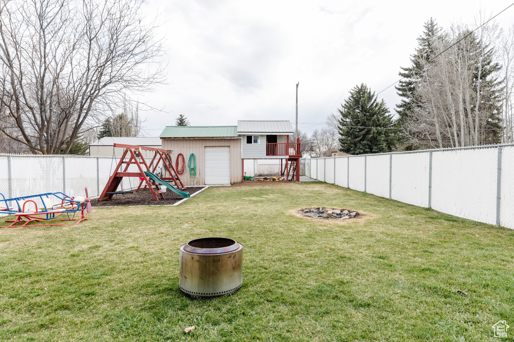 View of yard featuring an outdoor fire pit, an outdoor structure, and a playground