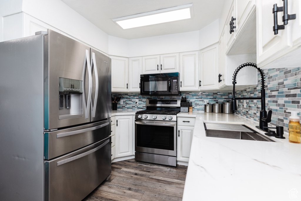 Kitchen featuring appliances with stainless steel finishes, white cabinetry, sink, and dark hardwood / wood-style floors