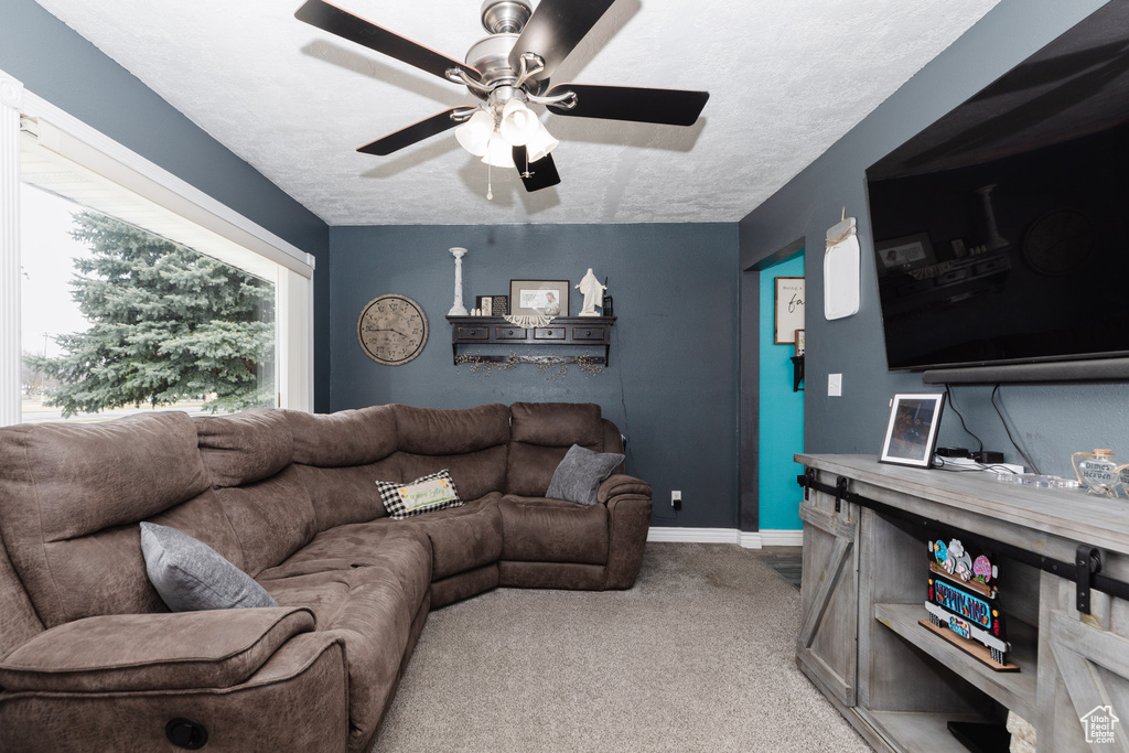 Living room featuring a textured ceiling, light colored carpet, and ceiling fan
