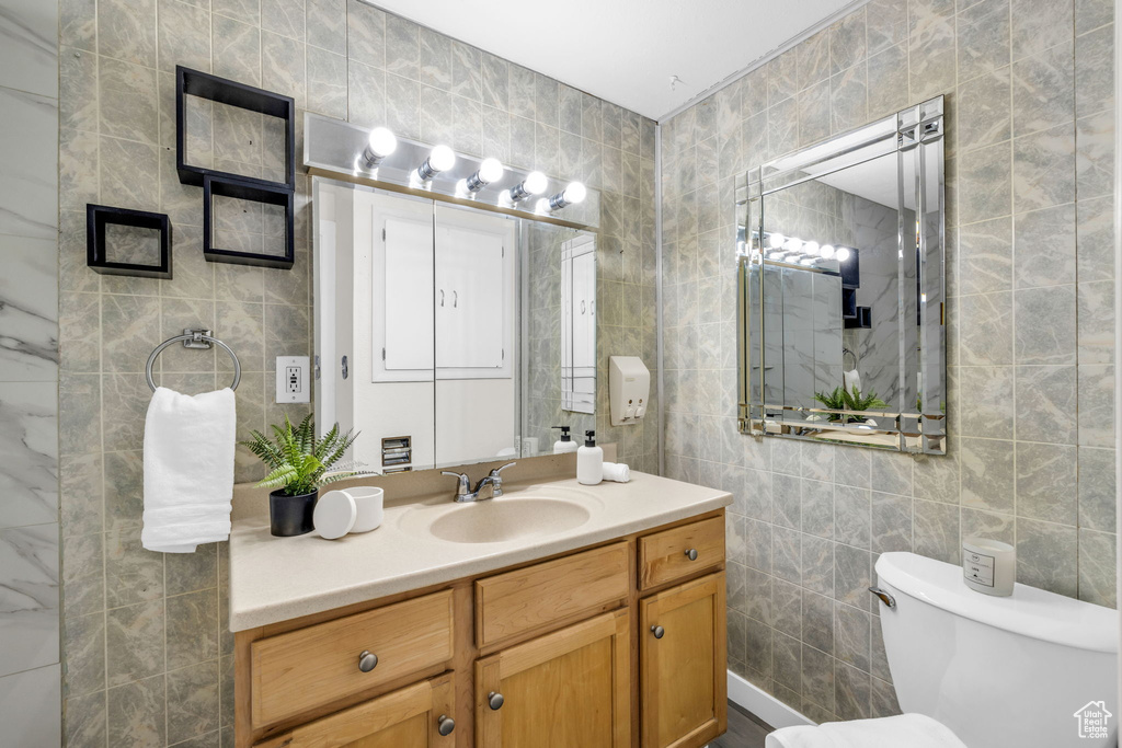 Bathroom featuring tile walls, oversized vanity, and toilet