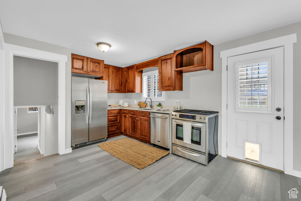 Kitchen with appliances with stainless steel finishes, sink, and light hardwood / wood-style floors