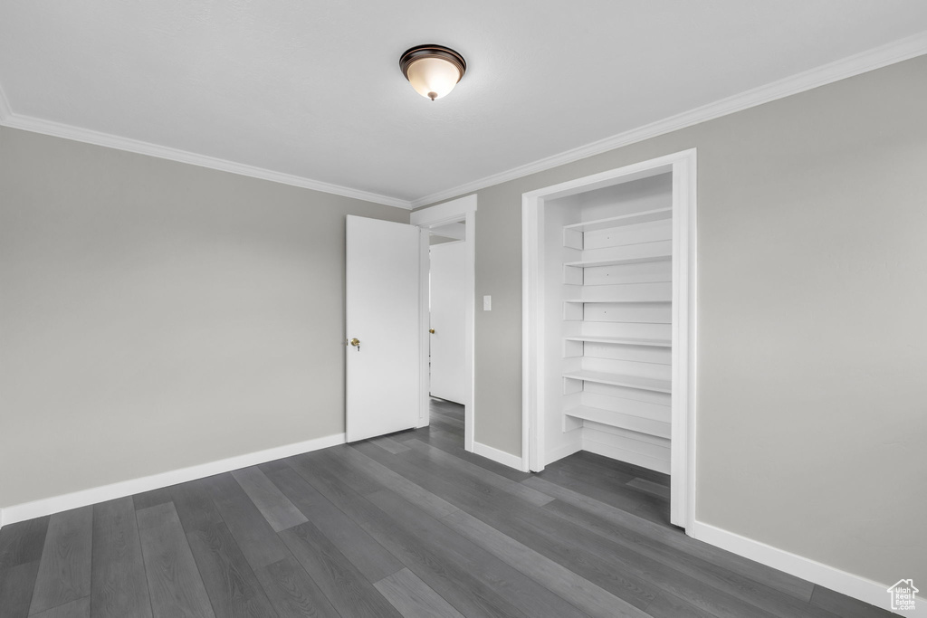 Unfurnished bedroom with dark hardwood / wood-style flooring, a closet, and crown molding
