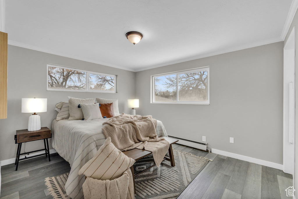 Bedroom with crown molding, baseboard heating, and dark hardwood / wood-style floors