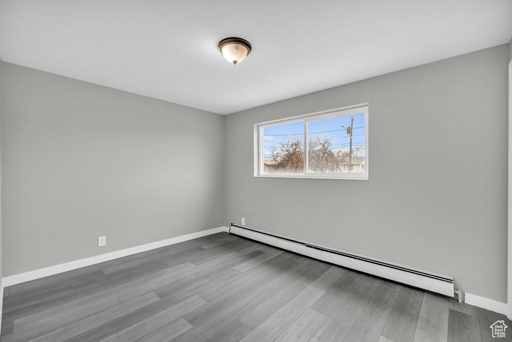 Empty room with dark wood-type flooring and baseboard heating