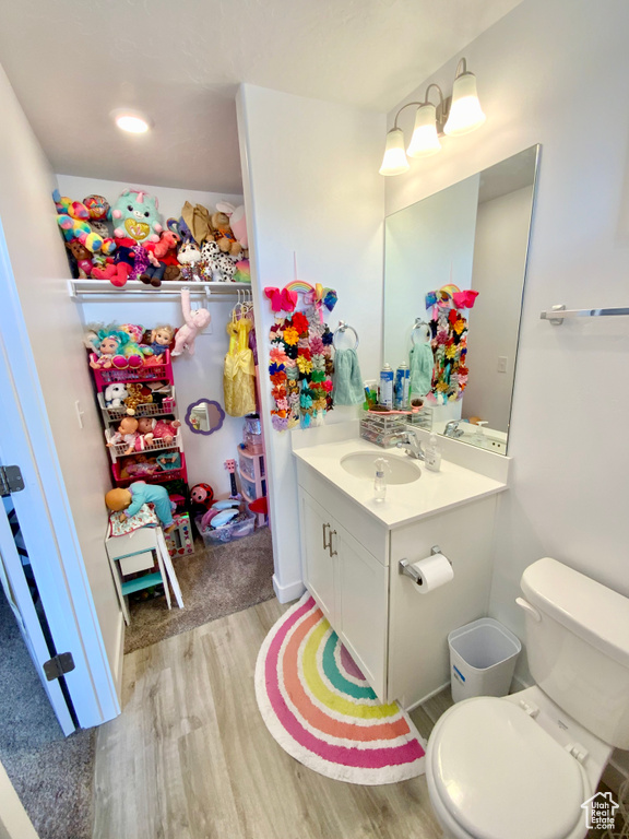 Bathroom with hardwood / wood-style floors, toilet, and vanity with extensive cabinet space