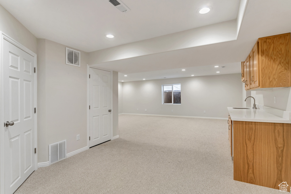 Basement featuring sink and light colored carpet