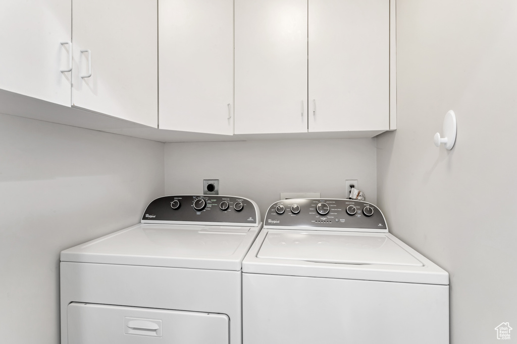 Laundry area with washing machine and dryer, electric dryer hookup, and cabinets