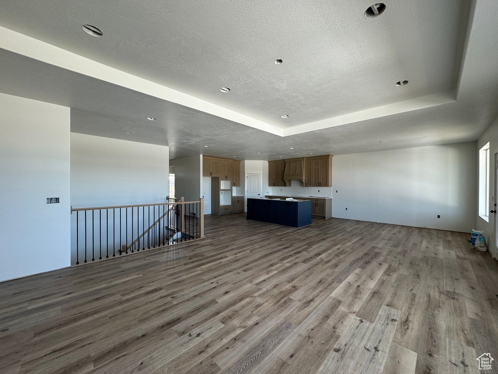 Unfurnished living room with light hardwood / wood-style floors and a raised ceiling