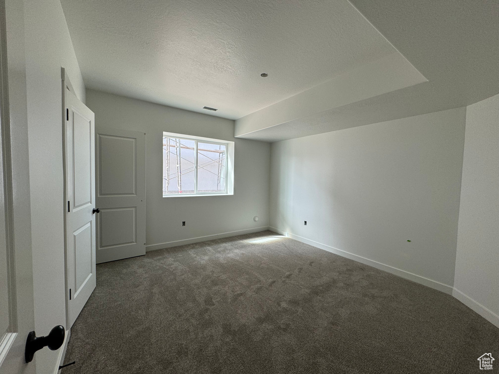 Spare room featuring dark carpet and a textured ceiling