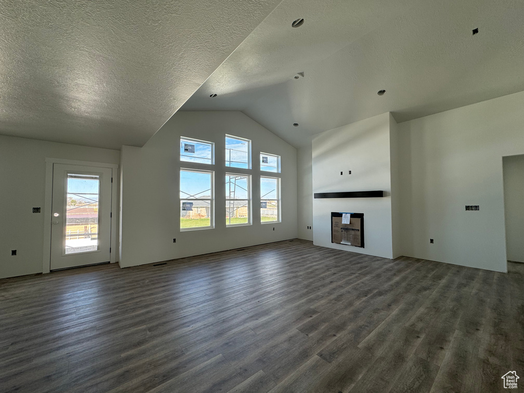 Unfurnished living room featuring lofted ceiling, a textured ceiling, and dark hardwood / wood-style floors