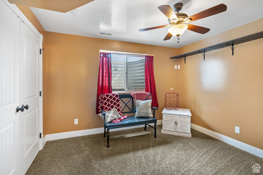 Living area featuring dark carpet and ceiling fan