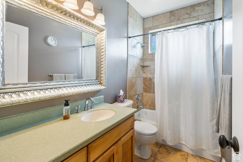 Full bathroom featuring vanity, toilet, tile flooring, and shower / bath combo with shower curtain