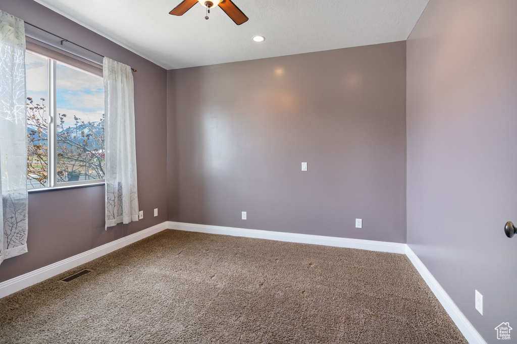 Unfurnished room featuring a healthy amount of sunlight, carpet, and ceiling fan