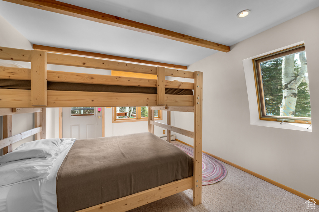 Carpeted bedroom featuring lofted ceiling with beams