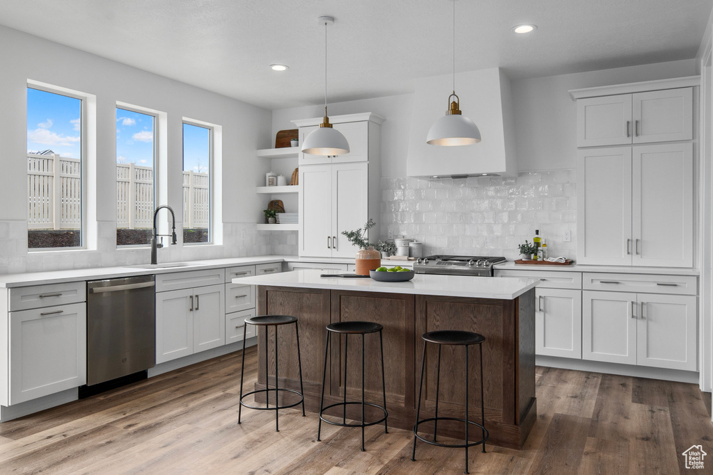 Kitchen featuring dishwasher, hanging light fixtures, a kitchen island, and backsplash