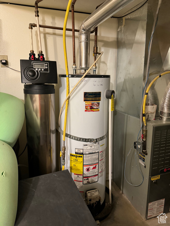 Utility room featuring strapped water heater